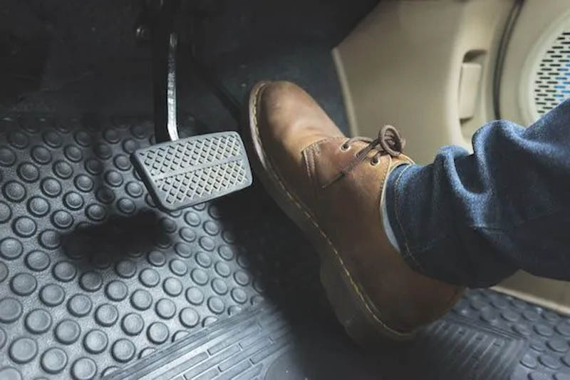 A seated individual wearing shoes on the car floor